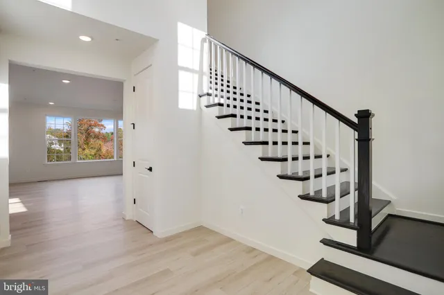 a view of an empty room with wooden floor and stairs