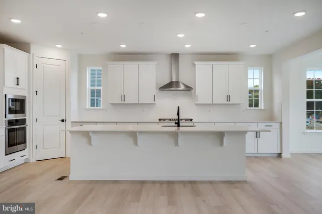 a large kitchen with stainless steel appliances granite countertop a lot of counter space and wooden floors