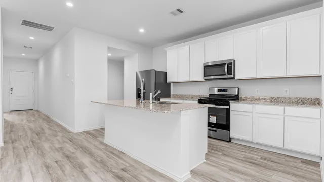 a kitchen with kitchen island white cabinets and stainless steel appliances