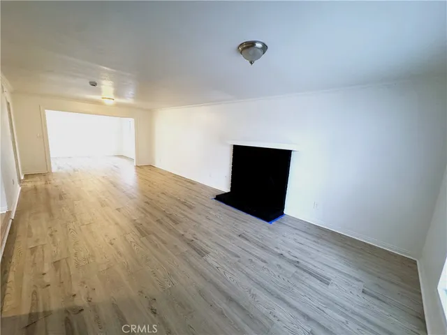 a view of a livingroom with wooden floor and a kitchen space
