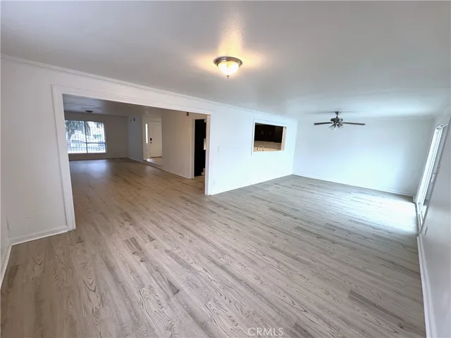 an empty room with wooden floor fan and windows