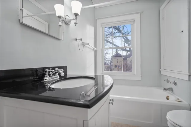 a bathroom with a granite countertop sink a toilet and bathtub