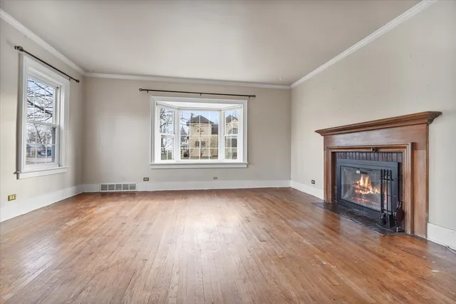 an empty room with wooden floor fireplace and windows