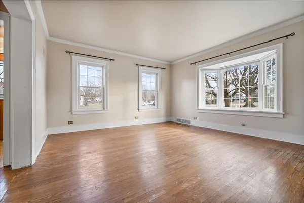 a view of an empty room with windows and wooden floor