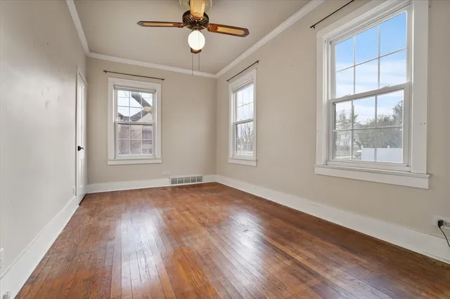 a view of an empty room with wooden floor and window