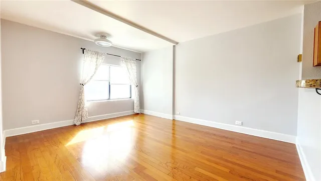 a view of an empty room with a window and wooden floor