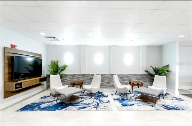 a view of kitchen with stainless steel appliances dining table chairs and flat screen tv