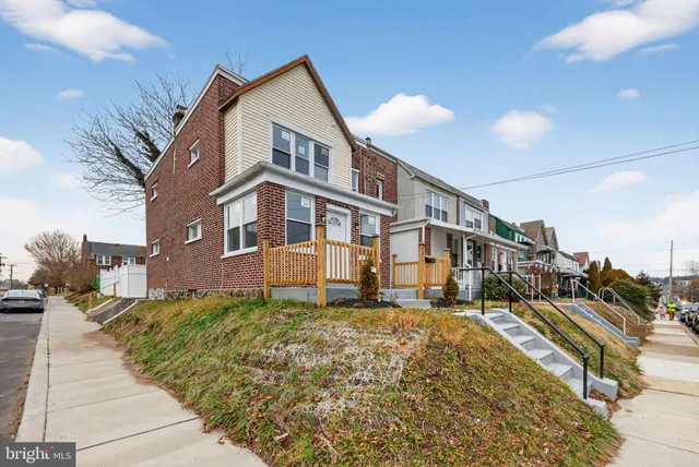 a view of residential houses with yard and car parked