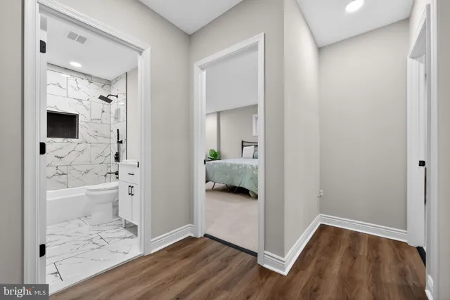 a view of a hallway with wooden floor and a bathroom