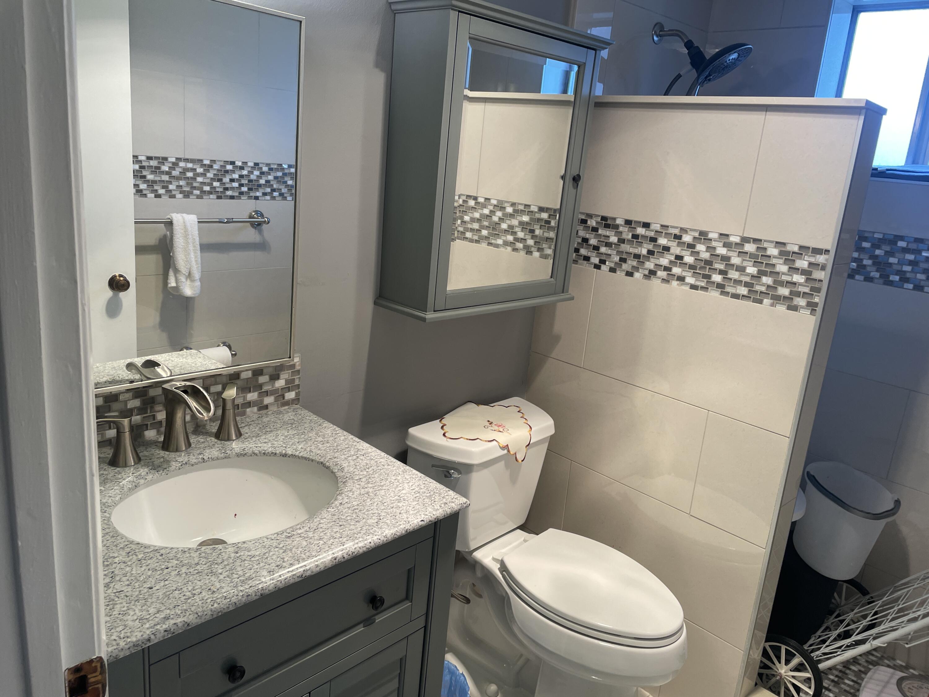 3300 Springdale Boulevard, Unit 201 Palm Springs, FL 33461 - Photo 40 of 49 a bathroom with a granite countertop toilet sink and mirror