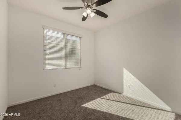 an empty room with a window and a fan