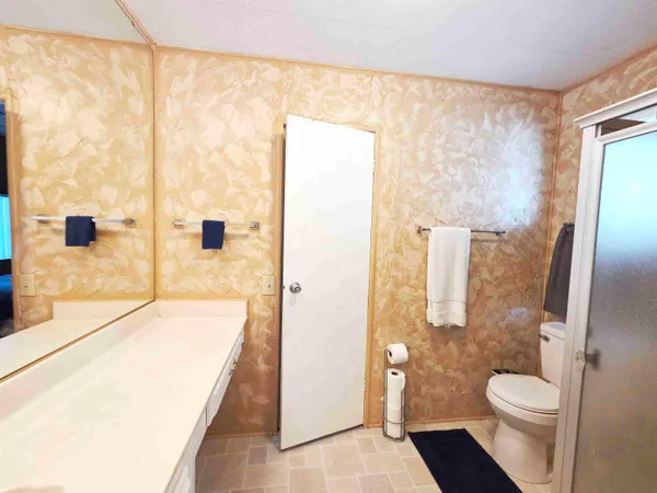 a bathroom with a granite countertop sink a toilet a large mirror and shower