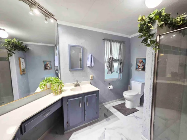 a spacious bathroom with a granite countertop sink a toilet a mirror and shower