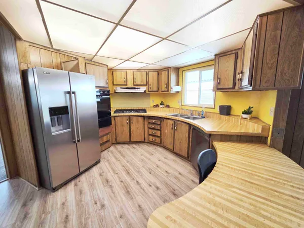 a kitchen with stainless steel appliances granite countertop a refrigerator a sink dishwasher a stove with wooden floors and cabinets