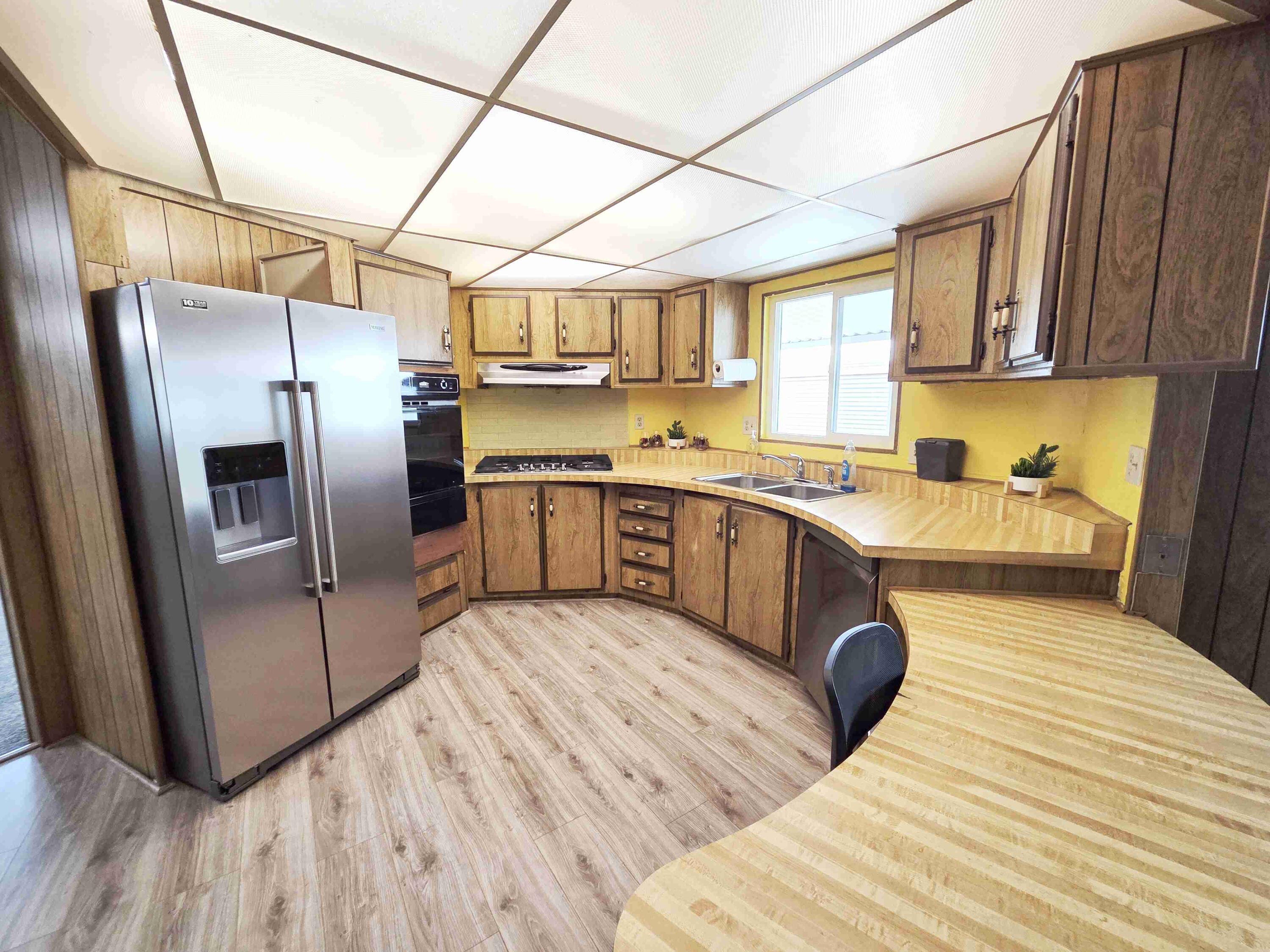 362 Buffalo Road Cathedral City, CA 92234 - Photo 9 of 15 a kitchen with stainless steel appliances granite countertop a refrigerator a sink dishwasher a stove with wooden floors and cabinets