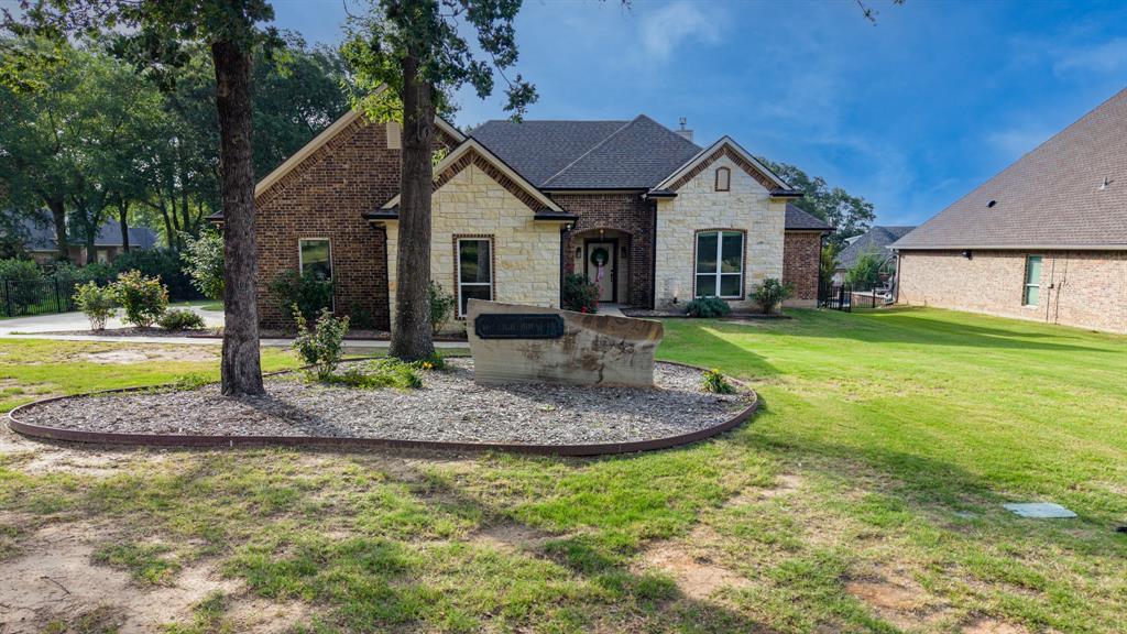 101 Lighthouse Lane Mabank, TX 75143 - Photo 1 of 40 Brick and stone facade residence featuring a dark shingle roof and a landscaped front yard with mature trees