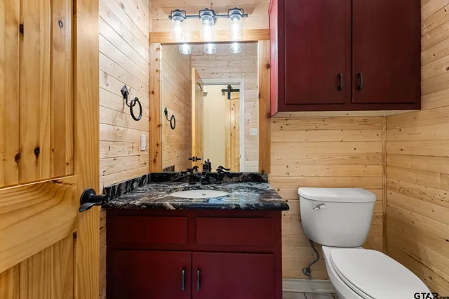 a bathroom with a granite countertop toilet sink and mirror