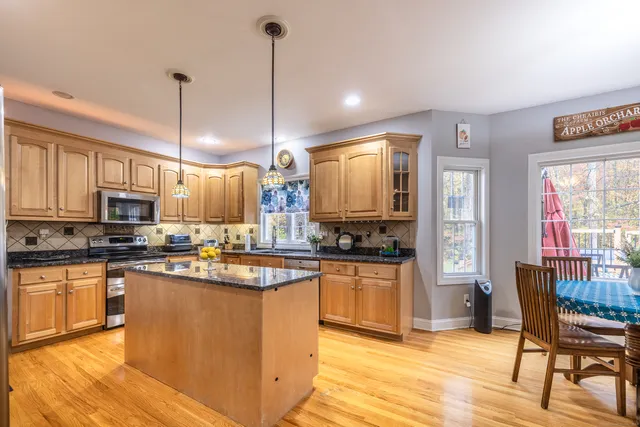 a kitchen with stainless steel appliances granite countertop a stove top oven a sink dishwasher a dining table and chairs with wooden floor