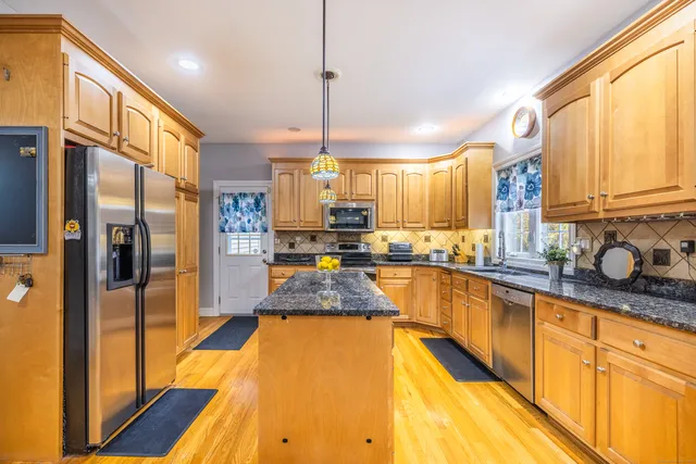 a large kitchen with granite countertop a large window and stainless steel appliances
