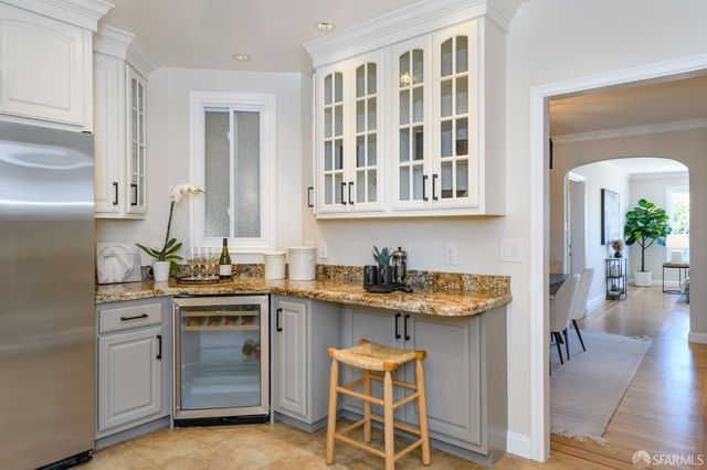 a kitchen with granite countertop a sink stove refrigerator and white cabinets