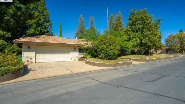 a view of yellow house with a yard and potted plants