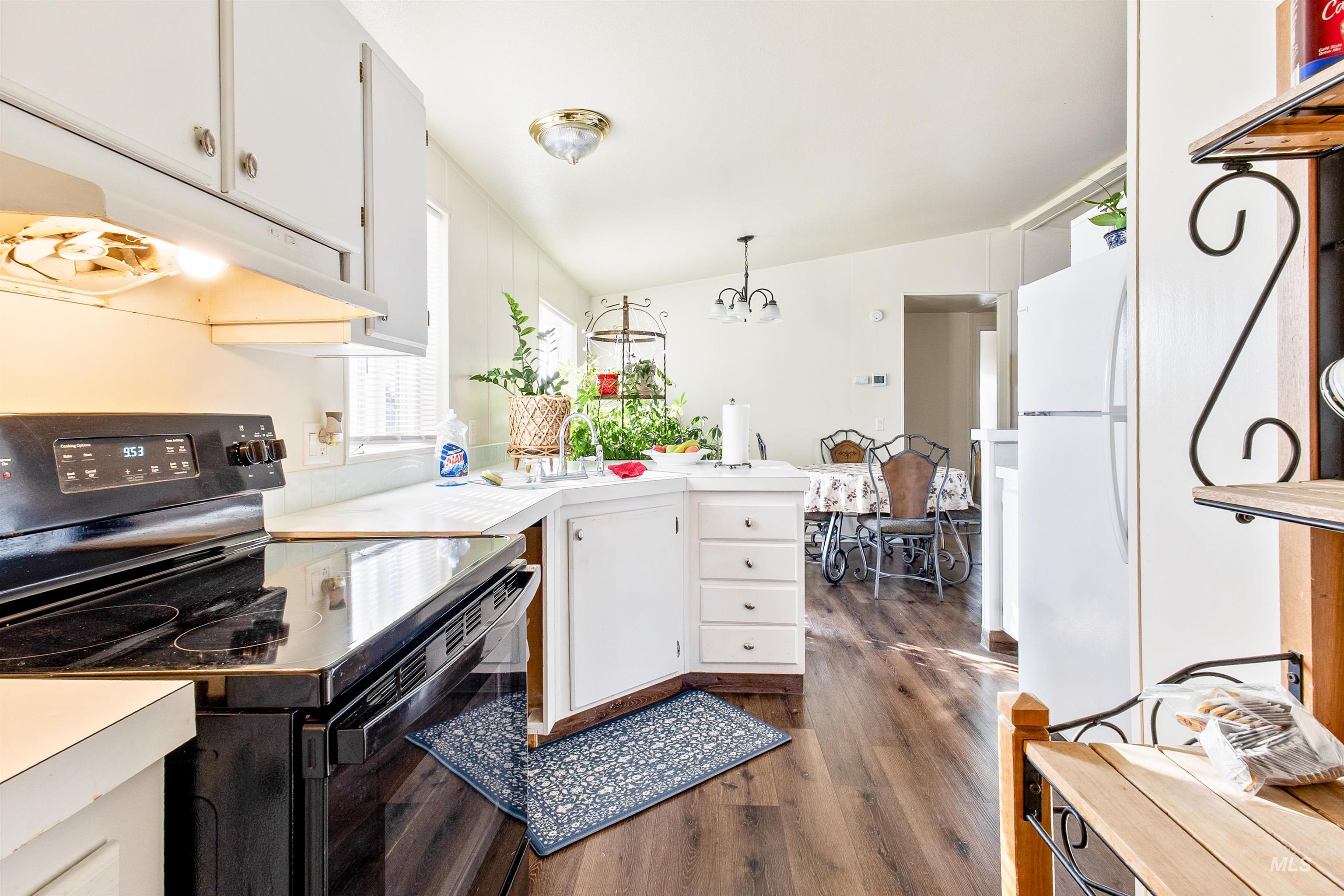 524 West Mesquite Street Boise, ID 83713 - Photo 11 of 29 Kitchen featuring black electric range oven, white cabinetry, light countertops, dark wood-style flooring, and freestanding refrigerator