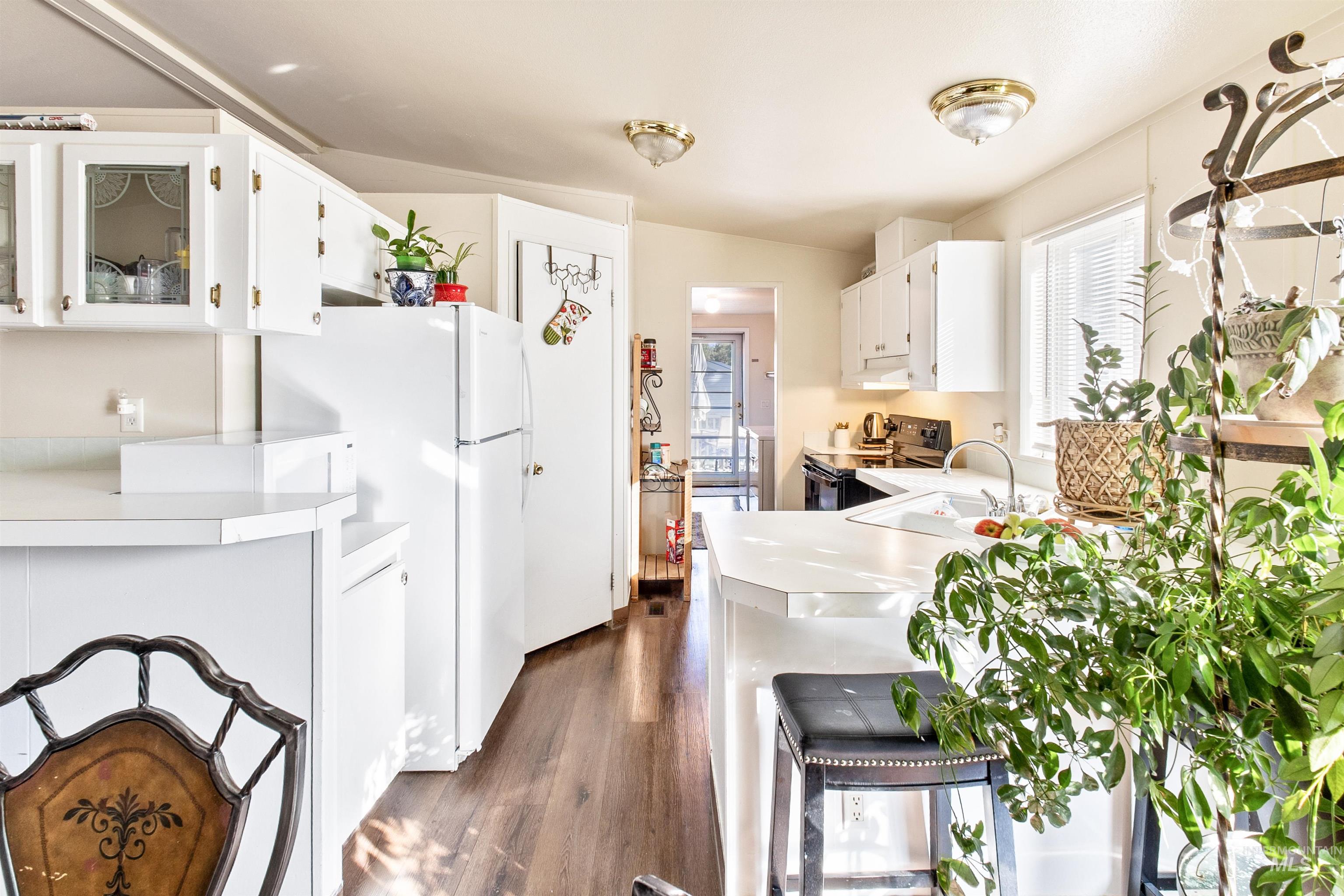 524 West Mesquite Street Boise, ID 83713 - Photo 14 of 29 Kitchen with light countertops, white cabinetry, dark wood-style floors, electric range, and a peninsula
