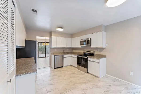 a kitchen with granite countertop a stove top oven microwave and cabinets