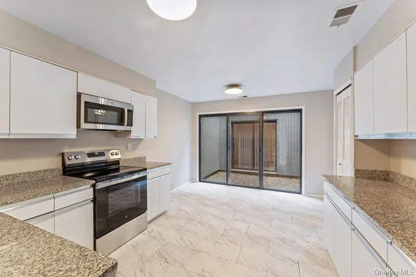 a large kitchen with granite countertop a stove a sink and a granite counter top