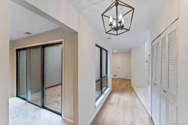 a view of a hallway with wooden floor and a chandelier