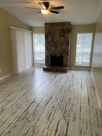 an empty room with wooden floor fireplace and windows