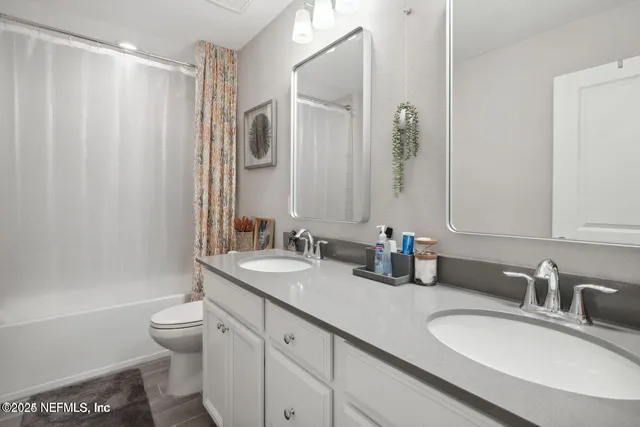 a bathroom with double vanity sink a toilet and a mirror
