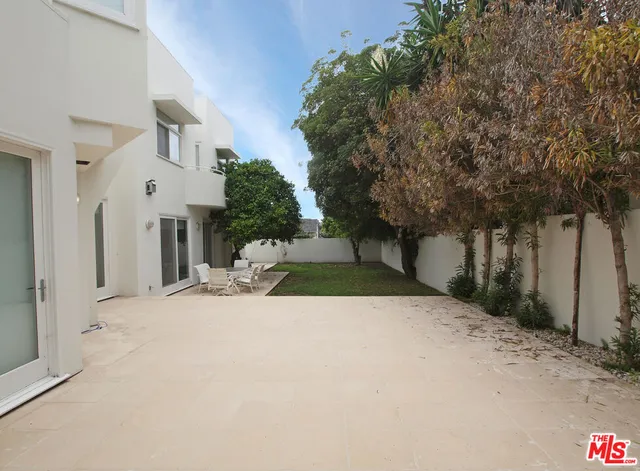 a view of a white house with a yard and tree