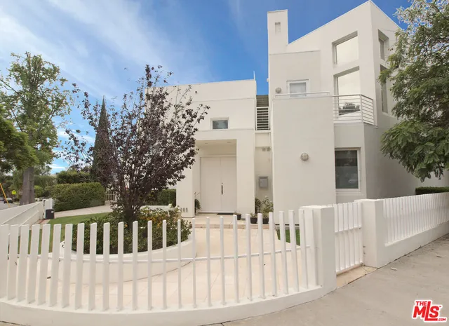 a view of a white house with wooden fence