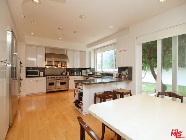 a kitchen with a refrigerator a stove a sink dishwasher with a dining table and chairs