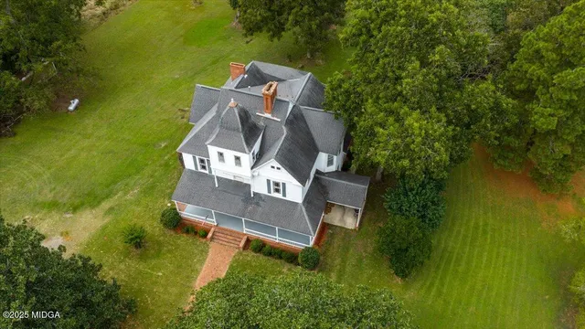 an aerial view of residential houses with outdoor space and trees all around