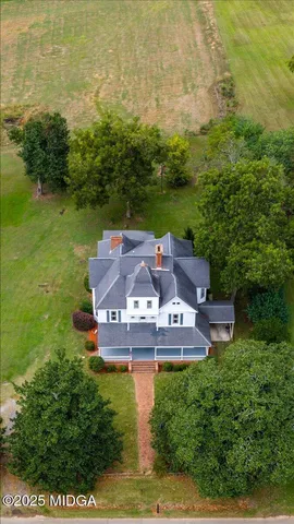 an aerial view of a house with a yard large trees all around