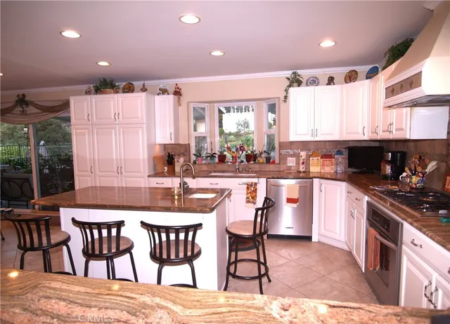 a kitchen with stainless steel appliances granite countertop a stove and a refrigerator with white cabinets