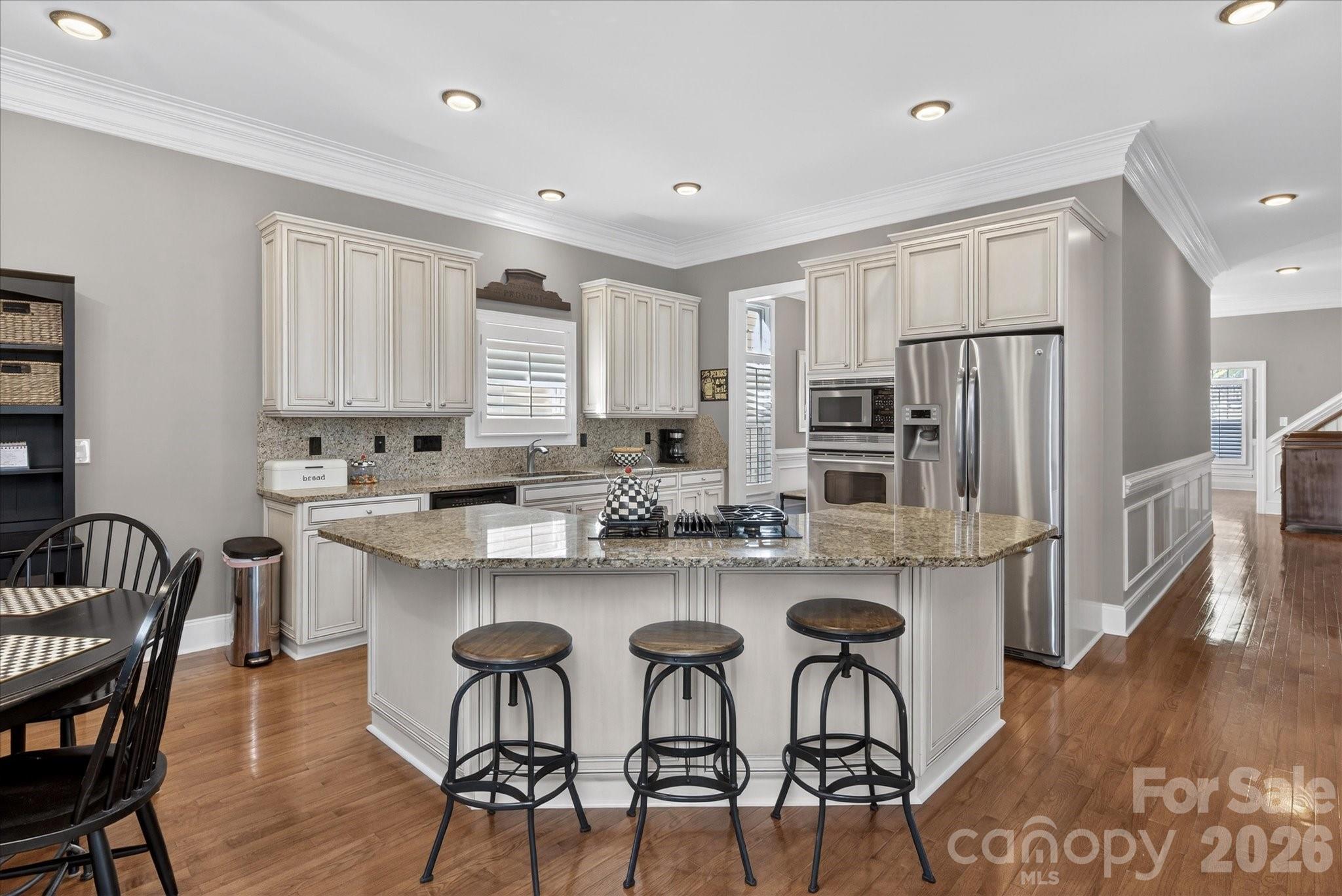 8811 1st Bloom Road Charlotte, NC 28277 - Photo 20 of 48 a kitchen with stainless steel appliances granite countertop a table chairs refrigerator and wooden cabinets