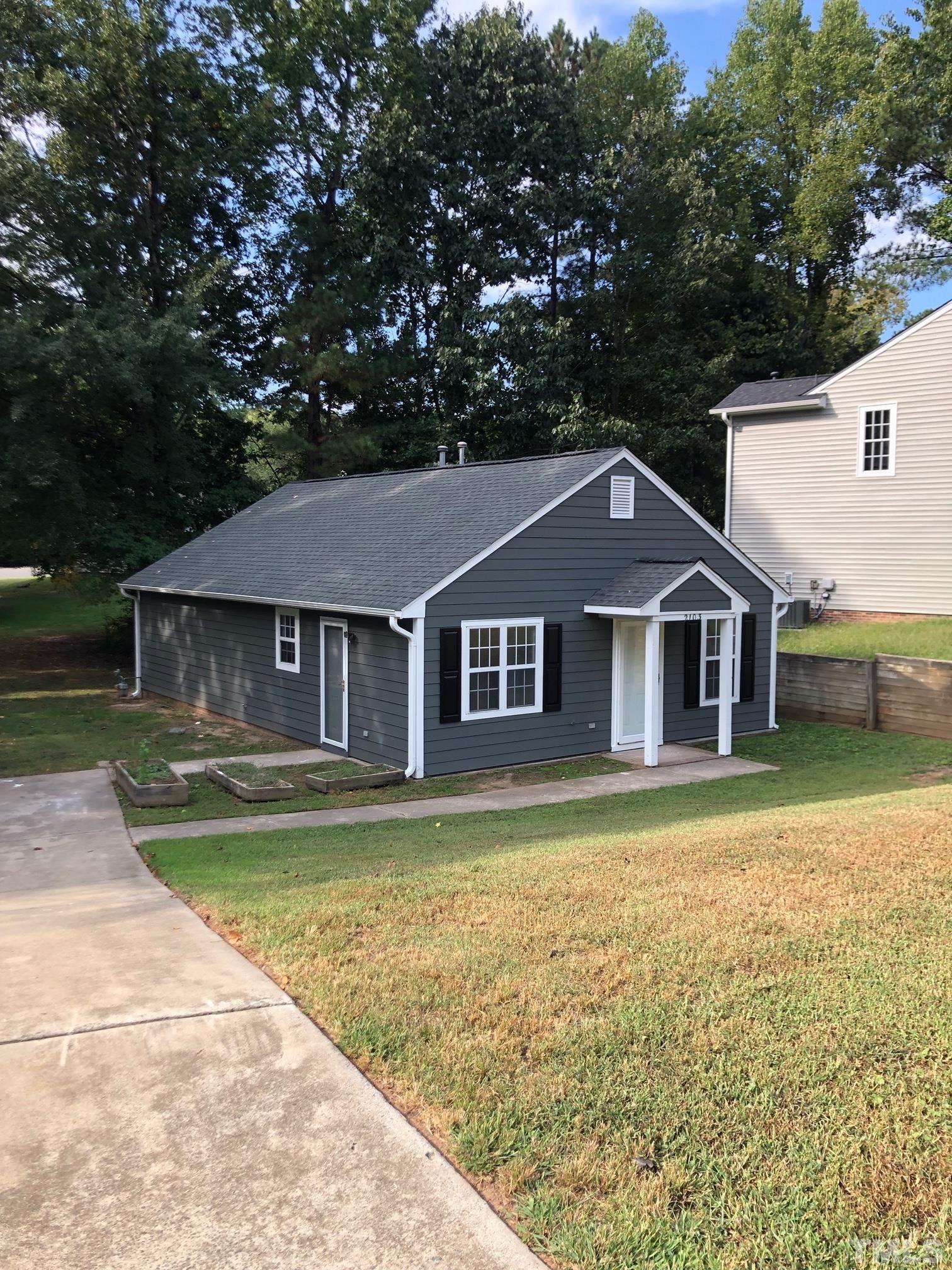 2103 Collier Road Durham, NC 27707 - Photo 2 of 23 a front view of a house with a garden and trees