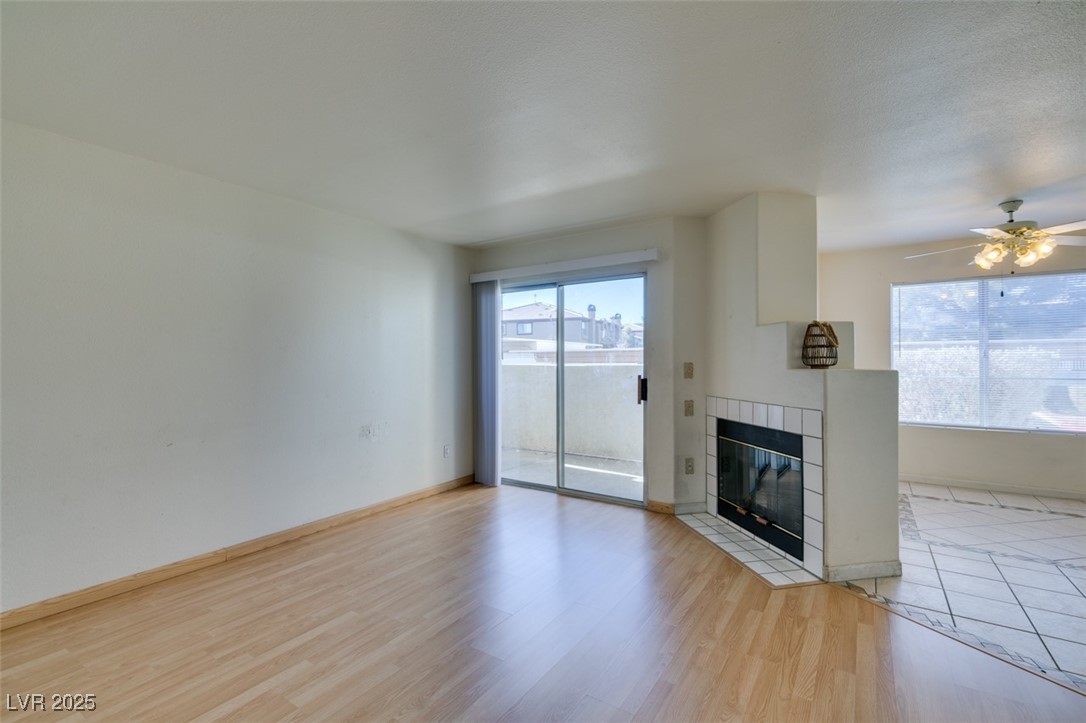 698 South Racetrack Road, Unit 711 Henderson, NV 89015 - Photo 8 of 25 Unfurnished living room with healthy amount of natural light, a fireplace, light wood-style floors, and ceiling fan