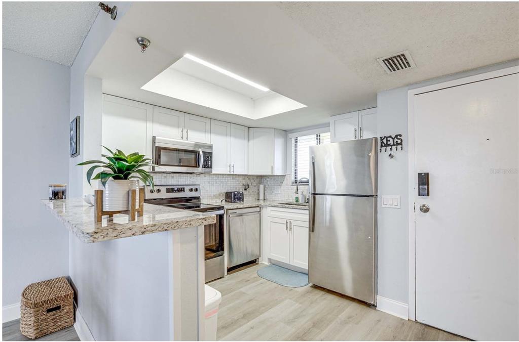 5915 Sea Ranch Drive, Unit 310 Hudson, FL 34667 - Photo 4 of 25 a kitchen with stainless steel appliances granite countertop a refrigerator a stove a sink a microwave a dining table and chairs