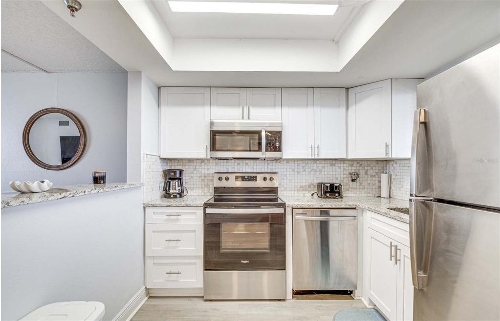 5915 Sea Ranch Drive, Unit 310 Hudson, FL 34667 - Photo 5 of 25 a kitchen with white cabinets and stainless steel appliances