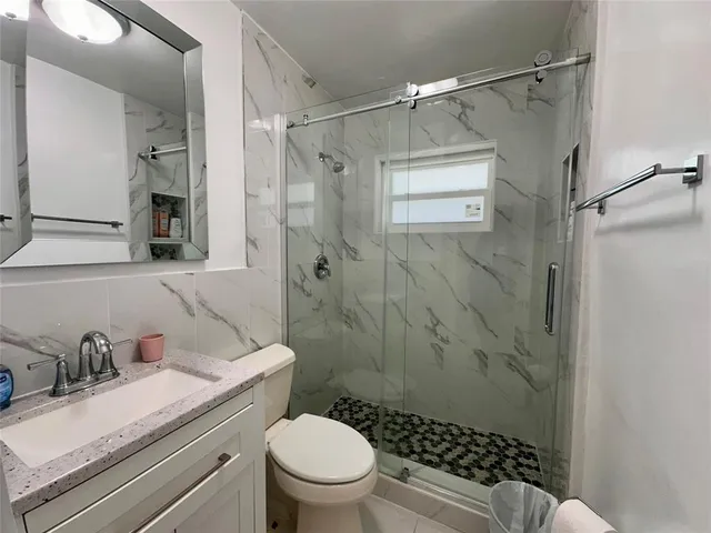 a bathroom with a granite countertop sink toilet and shower