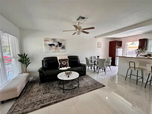 a living room with furniture and a dining table with wooden floor