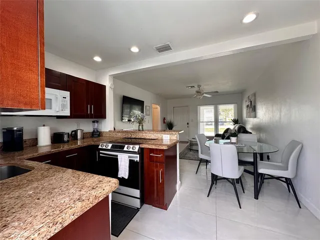 a kitchen with stainless steel appliances granite countertop table chairs sink and cabinets