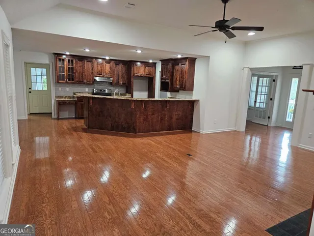 a living room with stainless steel appliances kitchen island granite countertop wooden floors and wide window