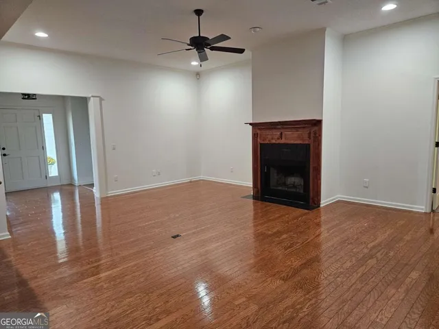 an empty room with wooden floor fireplace and ceiling fan