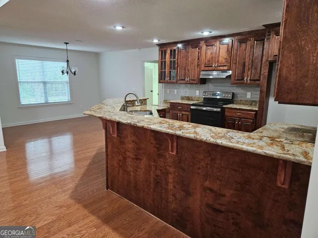 a view of an empty room with wooden floor and windows