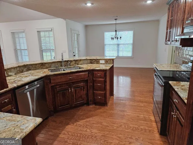 a kitchen with granite countertop kitchen island stainless steel appliances a stove refrigerator sink and cabinets